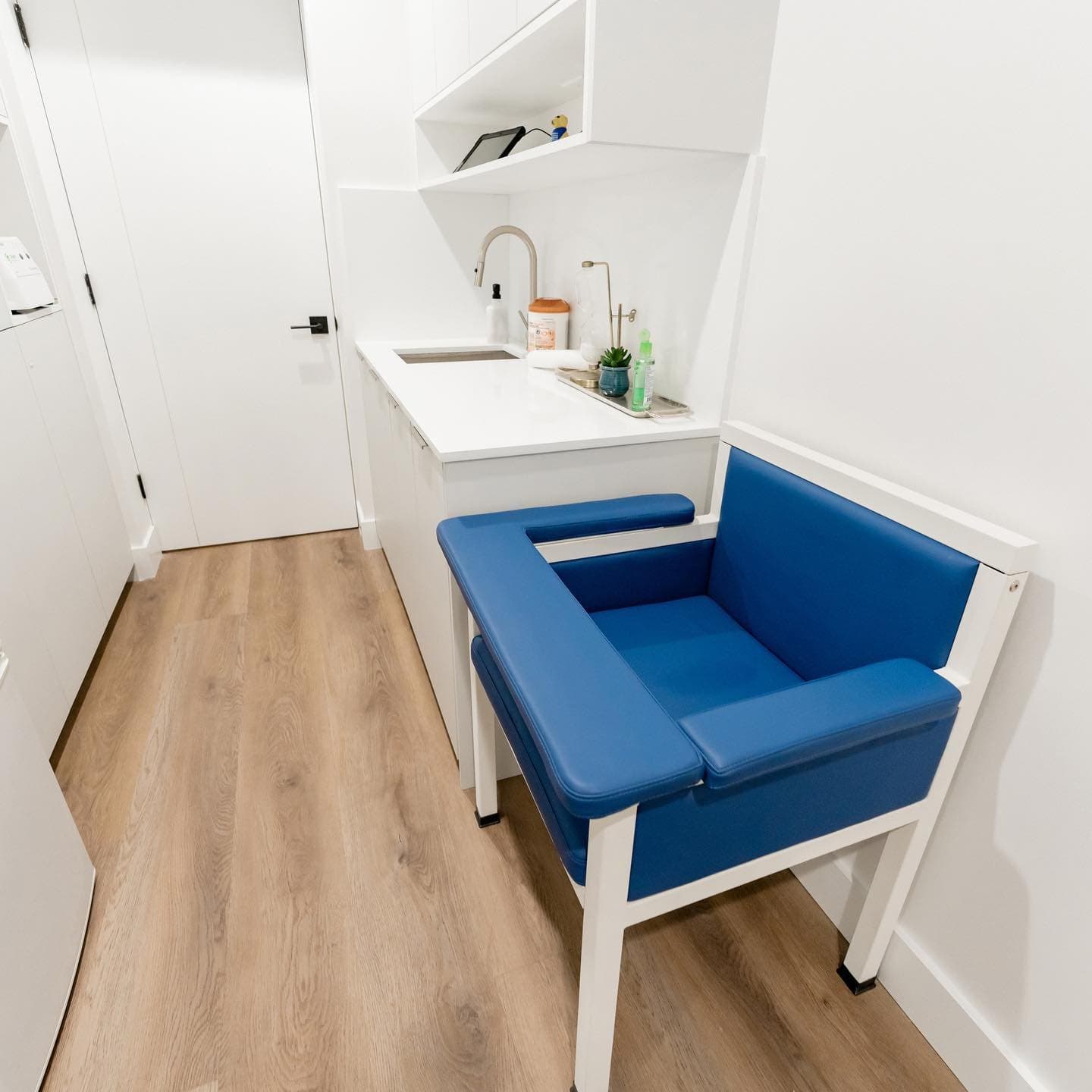 Exam room with a blue patient chair and sink